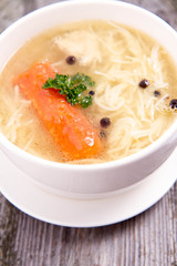Chicken soup with carrots and parsley on wooden background