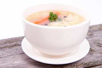 Chicken soup with carrots and parsley on wooden background