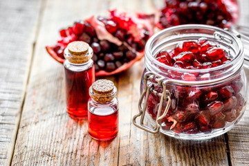 sliced pomegranate and extract in glass on wooden background