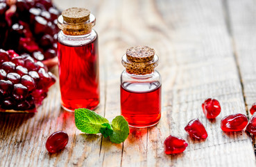 sliced pomegranate and extract in glass on wooden background