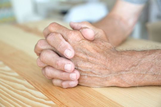 Senior man hands on table, closeup