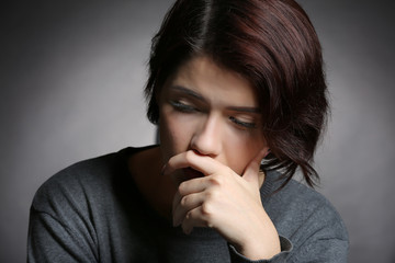 Fototapeta na wymiar Depressed young woman on grey background, closeup