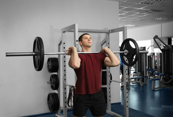 Fototapeta premium Young handsome man with barbell training in gym