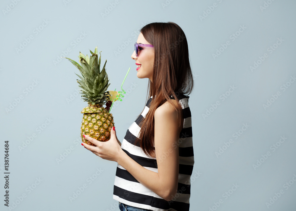 Poster Young beautiful woman with cocktail in pineapple on light background