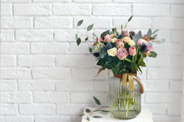 Glass vase with beautiful bouquet on brick wall background