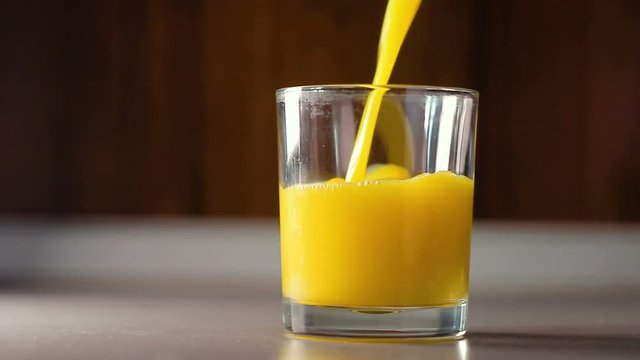 Pour the orange juice into a transparent glass, HD footage