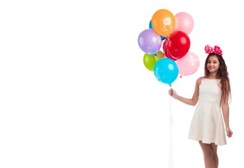 Lovely girl brunette with long hair in a white dress with a bow on her head and balloons posing on...