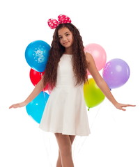 Lovely girl brunette with long hair in a white dress with a bow on her head and balloons posing on...