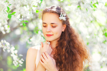 Naklejka premium Portrait beautiful young woman over flowering spring garden background