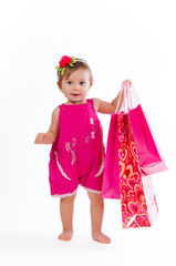 Little girl standing with colorful paper bags isolated on white background.