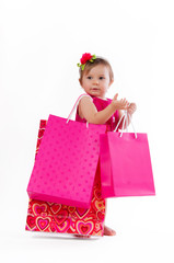 Little girl standing with colorful paper bags isolated on white background.
