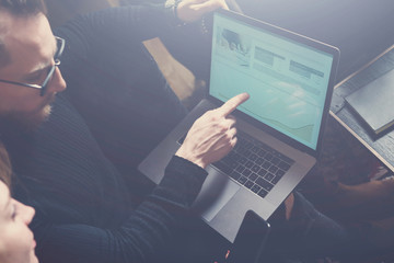 Teamwork process concept.Two young colleagues using computer.Woman wearing black pullover and sitting on the sofa.Graphs and diagramm on laptop screen.Horizontal, visual effects.