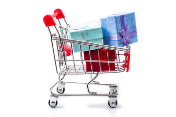 Christmas shopping and Holiday gift giving concept with steel shopping cart containing colorful gift boxes and Xmas presents isolated on white background