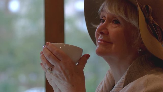 Senior woman drinking from cup. Thoughtful lady indoors. Be at peace with yourself.
