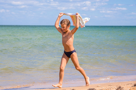 Boy running on coastline with towel