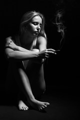 young woman sitting in dark smoking cigarette, monochrome
