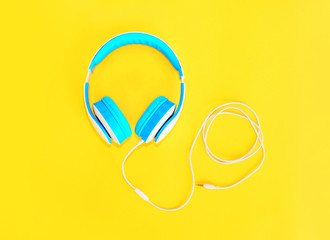 Blue headphones lie on colorful yellow background