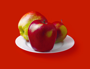 Apples on a plate isolated on red background