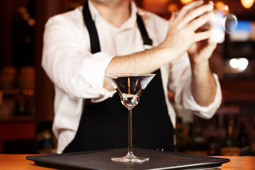 Barman in making cocktail at a nightclub. Nightlife concept. No face. Shaking drink