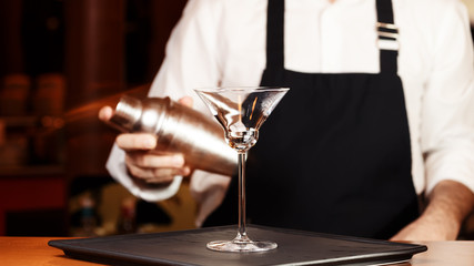Barman in making cocktail at a nightclub. Nightlife concept. No face. Shaking drink