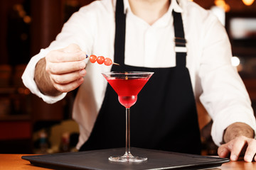 Barman in making cocktail at a nightclub. Nightlife concept. No face. Decorating drink