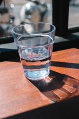 Glass of water on the wooden table with high