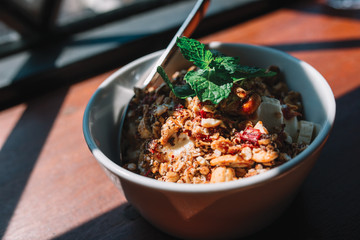 The bowl with smoothie, muesli, fruits and berries on the wooden table