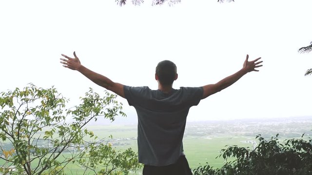 Successful man raising arms after cross track running on summer sunset. Fitness male athlete with arms up celebrating success and goals after sport exercising and working out.
