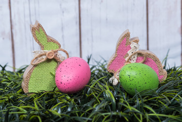 Rabbits and eggs on grass.   Crafted rabbits and decorated eggs arranged on grass.