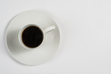 Top view of a white cup of coffee on white saucer