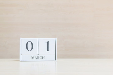 Closeup surface white wooden calendar with black 1 march word on blurred brown wood desk and wood wall textured background with copy space , selective focus at the calendar