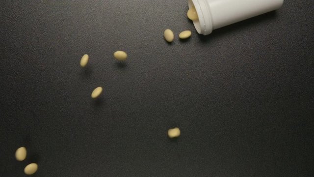 TOP VIEW: Plastic tube falls and pills fall out of him (slow motion)