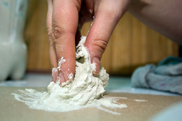 close up hands of ceramist  with white clay