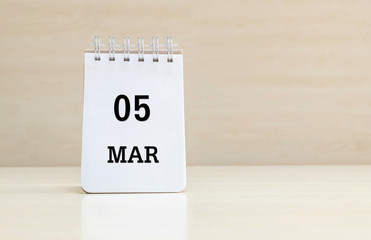Closeup surface note book with black 5 mar word in page on blurred brown wood desk and wood wall textured background with copy space under window light