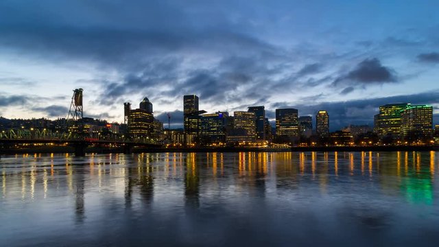 Time lapse movie of dark moving clouds and auto traffic downtown city of Portland Oregon along Willamette River with Hawthorne bridge and water reflection blue hour at night 4k uhd