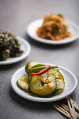 Korean cucumber kimchi on a white dish, More kimchi in the background. 