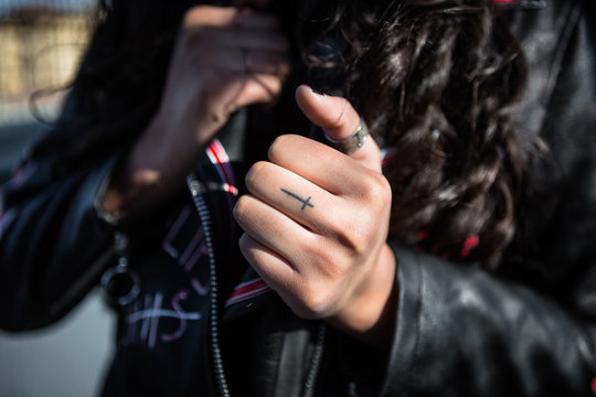 Little Cross Tattoo on the Hand of a Female Rocker