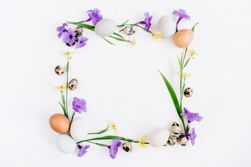 Frame wreath made of Easter eggs, quail eggs, yellow and purple flowers on white background. Flat lay, top view. Traditional spring concept. Easter concept.