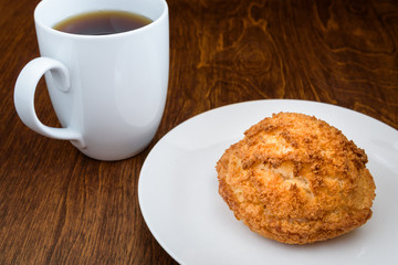 Homemade macaroon on a white plate, with a white coffee cup on a wood table 
