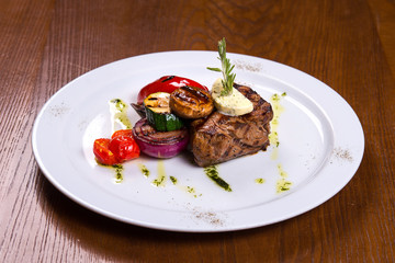 thick steak with rosemary and fried vegetables cheese on white plate