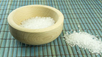 Sea salt in a wooden mortar on a wood background