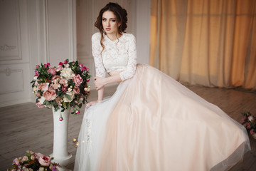 Girl with make-up in a wedding dress sits in a beautiful room