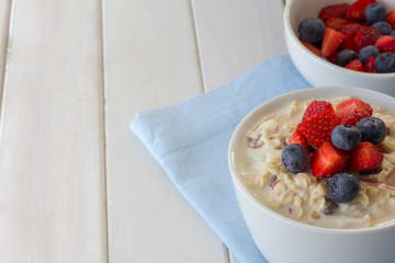 Bircher Muesli and Fresh Berries on White Wooden Table with Copy Space Horizontal