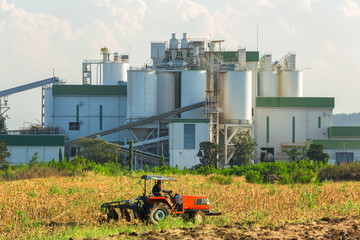 Ethanol industrial refinery with farm tractors in the foreground
