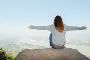 Young woman happy and relaxing in mountains with sunlight