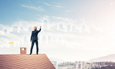 Man architect draw silhouette of modern city on blue sky. Mixed 