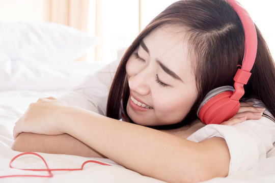 Young beautiful woman in bright outfit enjoying the music in headphones by smartphone and tablet at home, relax concept