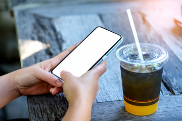 Hand playing smart phone with orange juice.