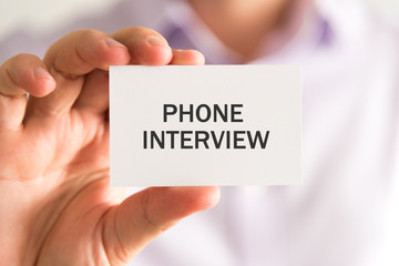 Businessman holding a card with PHONE INTERVIEW message