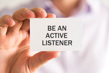 Businessman holding a card with BE AN ACTIVE LISTENER message